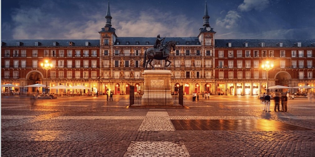 A historic plaza with a statue of a mounted figure, ornate buildings, and a cobblestone ground. 4