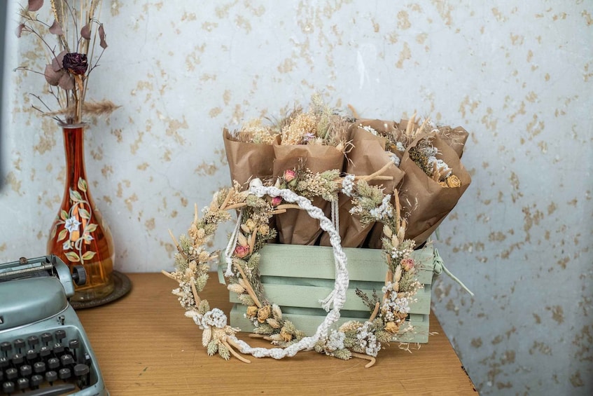 A vintage typewriter, a vase with dried flowers, and a rustic wooden crate with bouquets and a wreath. 2