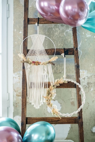 A macrame wall hanging with dried flowers and a macrame hoop on a wooden ladder. 3