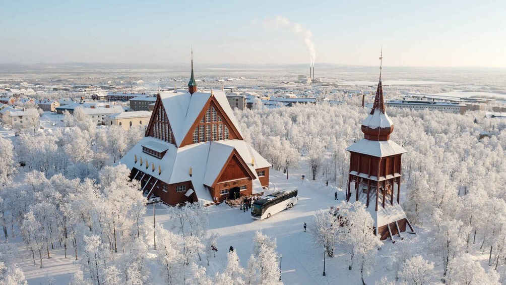 A snow-covered church with a bell tower and a large building with a steep roof. 3