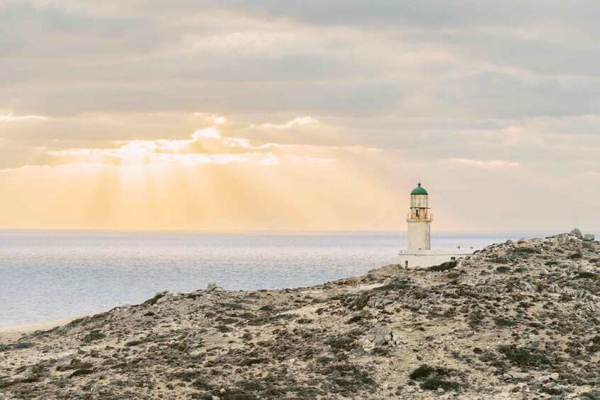 A lighthouse on a rocky coastline with the sea in the background and a cloudy sky. 5