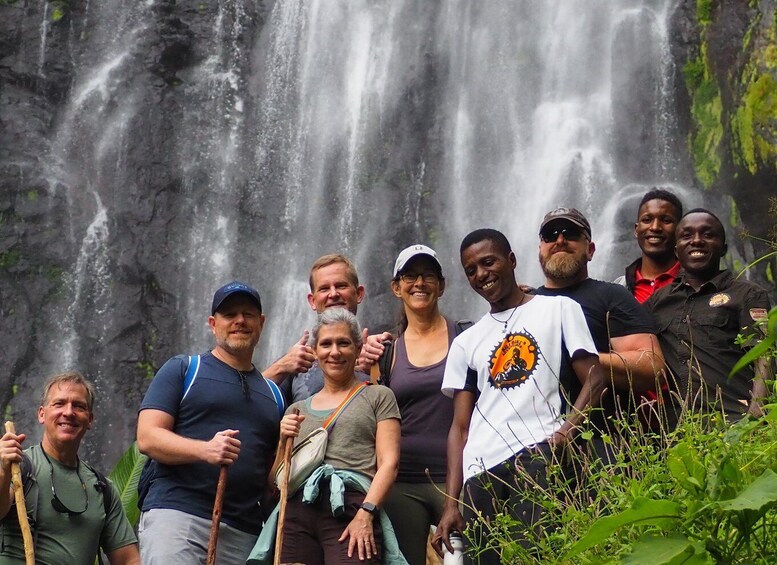 A group of people posing in front of a waterfall with lush greenery around. 3