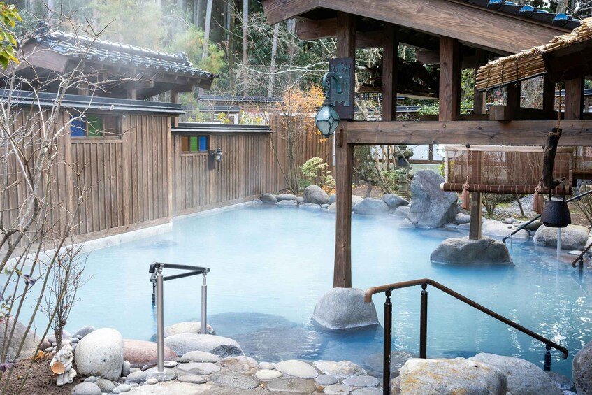 A traditional Japanese onsen with a wooden structure, a stone pool, and a rocky landscape. 3
