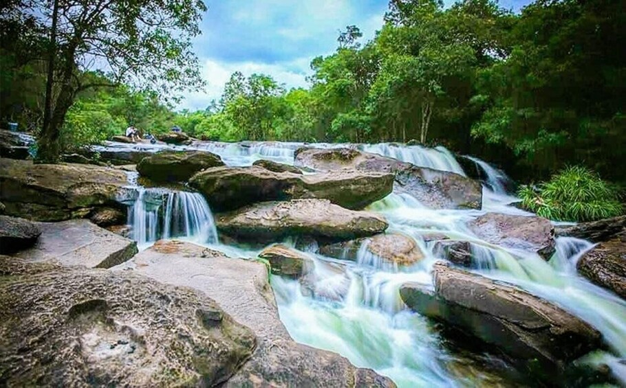 A waterfall cascading over large rocks in a forested area. 5