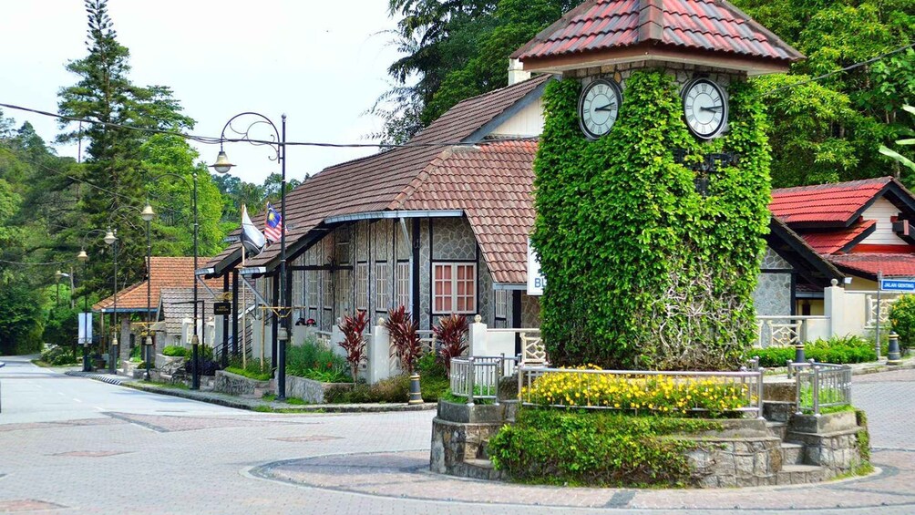 A clock tower with ivy, surrounded by a cobblestone plaza, and traditional buildings with red roofs. 5