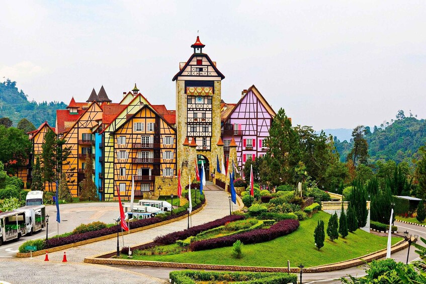 A colorful building with a tower, surrounded by lush greenery and a paved road. 1