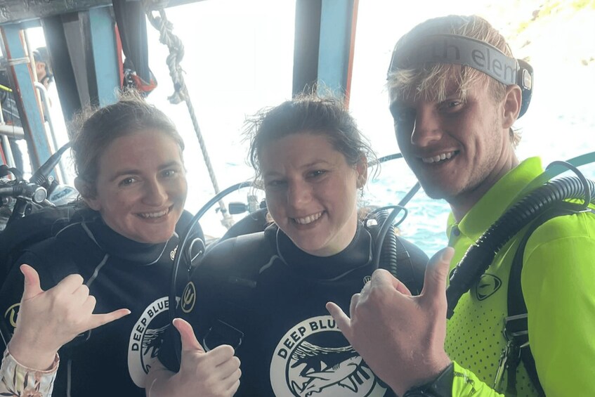 Three people in scuba diving gear with a logo that reads 'DEEP BLUE' on their wetsuits. 2
