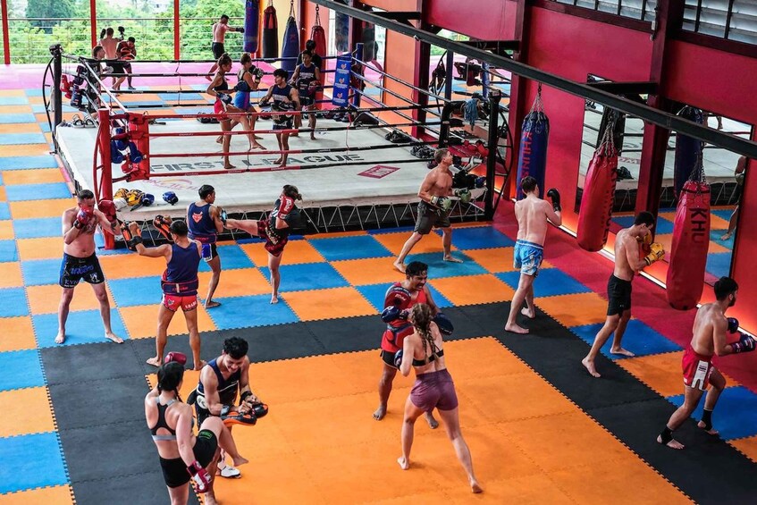 A boxing gym with a checkered floor, punching bags, and people training. 2