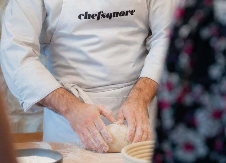 A person kneading dough with a bowl of flour nearby. 3