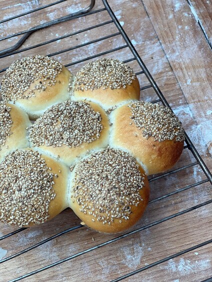 Six sesame seed buns on a wire cooling rack. 1