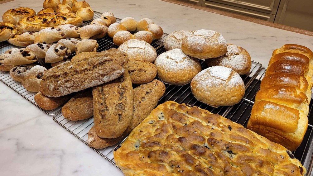 An assortment of breads and pastries on a cooling rack. 4