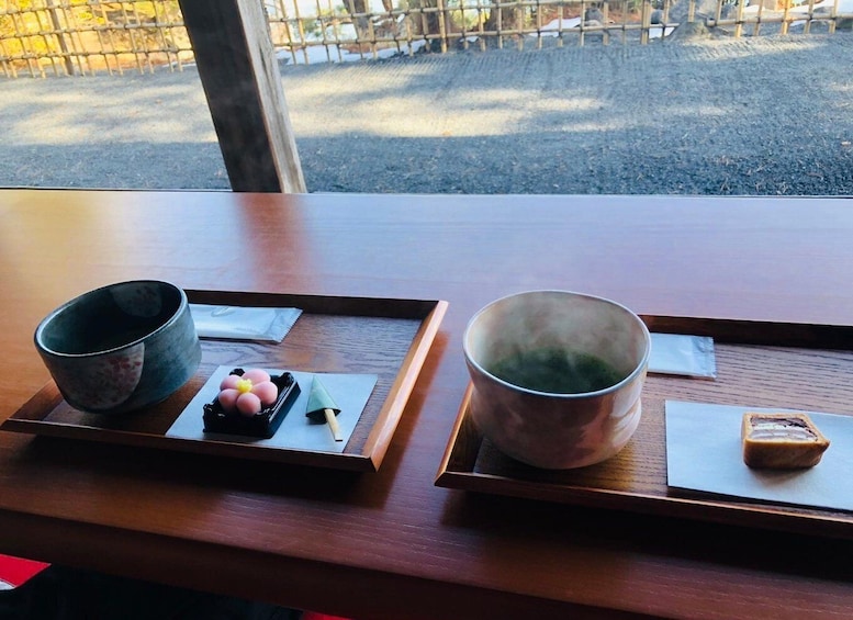 A wooden table with two trays, each holding a cup and a small dish with food. 3