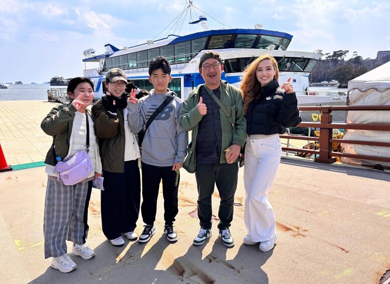 A group of people standing on a dock with a boat in the background. 4