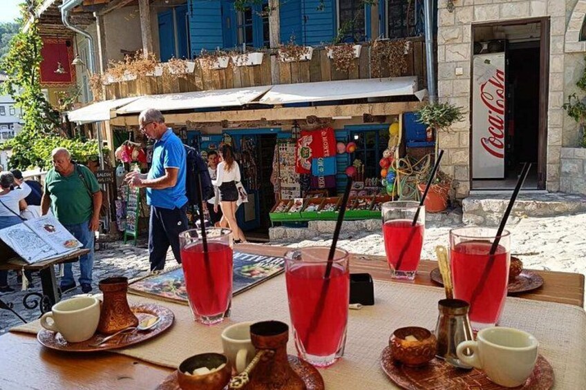 A table with red drinks, a Coca-Cola sign, and a man in a blue shirt. 3
