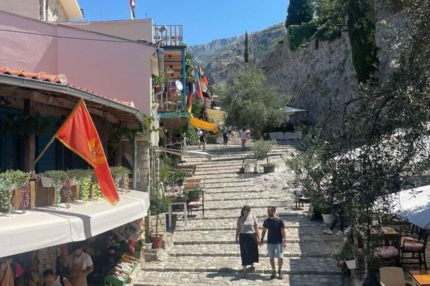 A stone staircase leading up a hillside, with buildings and flags on either side. 4