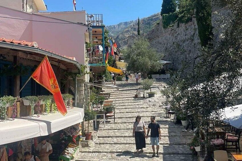A stone staircase leading up a hillside, with buildings on either side and flags hanging from the balconies. 4