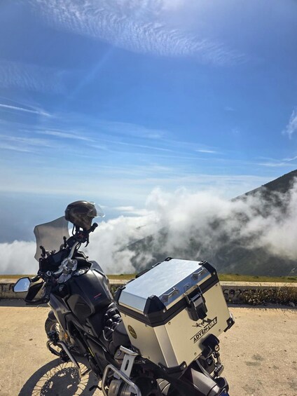 A motorcycle with a sidecar parked on a road with a mountainous backdrop and clouds. 4