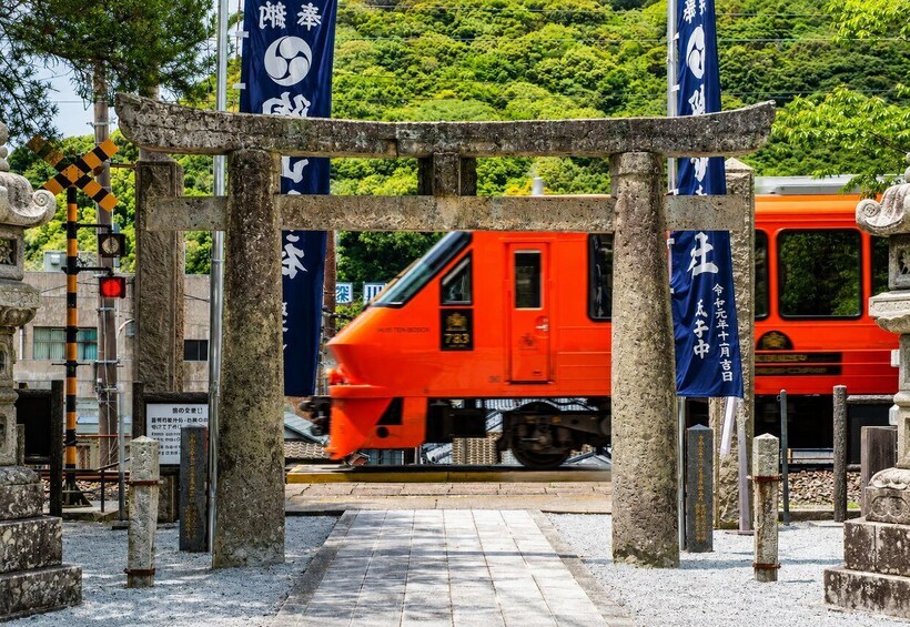 A red train passing through a traditional Japanese gate with banners. 1