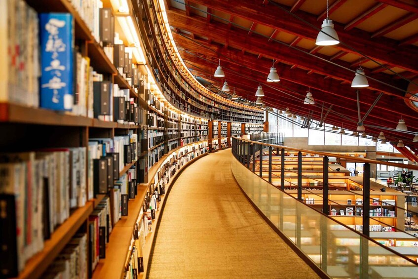 A curved library interior with bookshelves, wooden floors, and hanging lights. 5