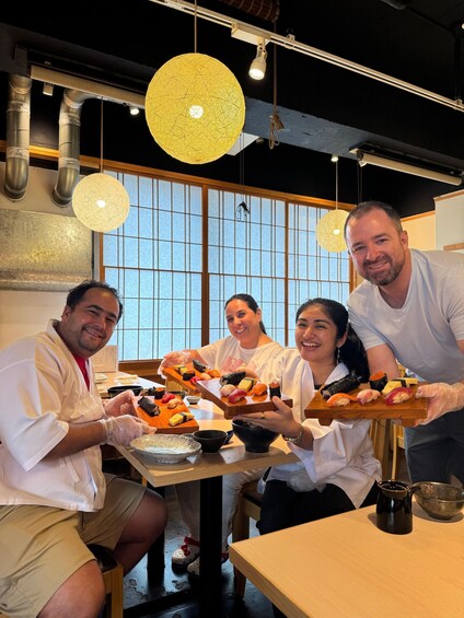 A group of people in a restaurant, holding trays of sushi. 3