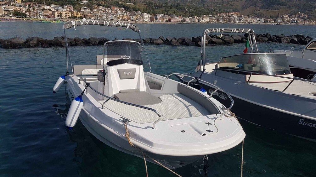 A white motorboat docked at a marina with a cityscape in the background. 2