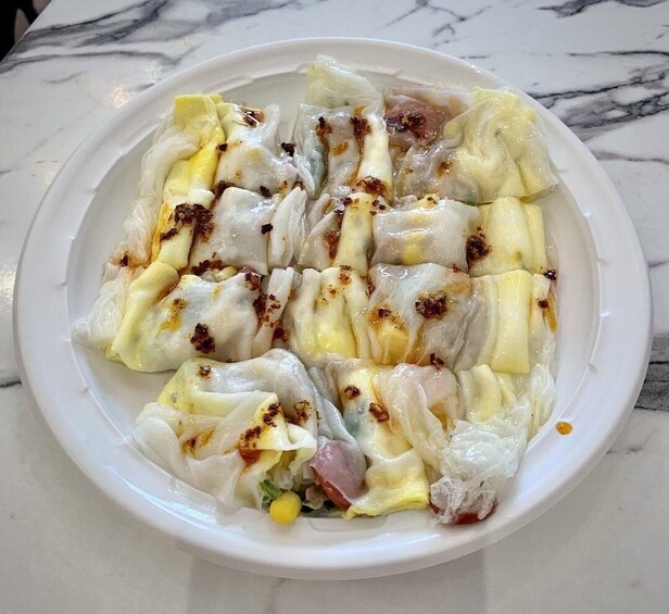 A plate of dumplings with a sauce and fried bits on top. 5
