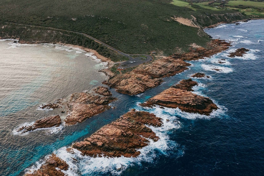 A coastal landscape with rocky formations, a winding road, and a body of water. 1