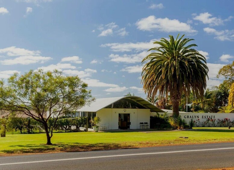A building with a curved roof, a large palm tree, and a sign that reads 'GRALIN ESTATE'. 4