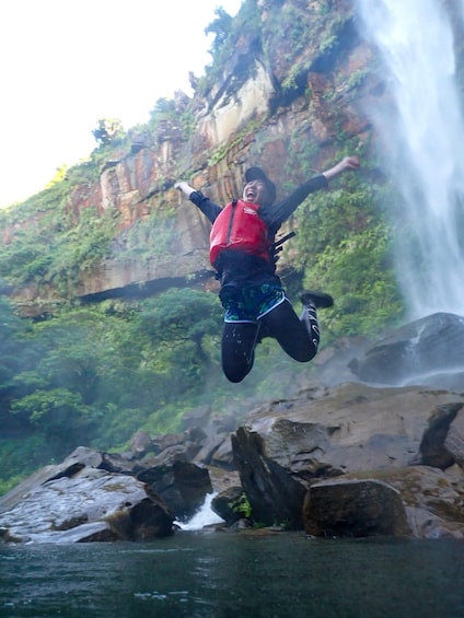 A person jumping in mid-air with a waterfall in the background. 4