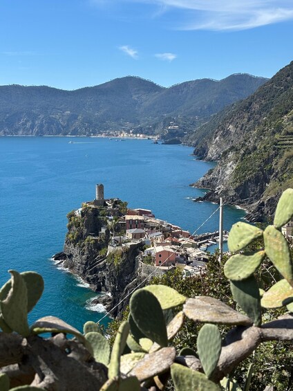 A coastal town with buildings on a cliff, a tower, and a clear blue sea. 1