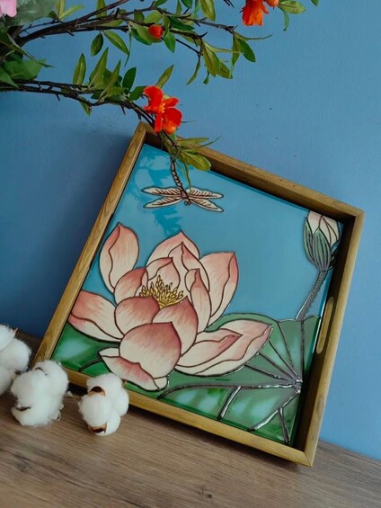 A framed artwork of a pink lotus flower with a dragonfly, cotton, and a branch with red flowers. 1