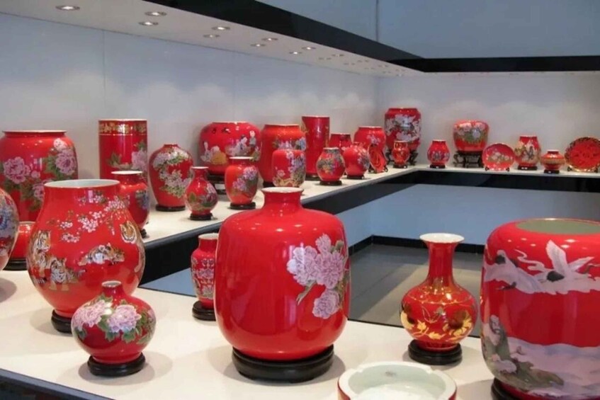A collection of red vases with floral designs on display. 2