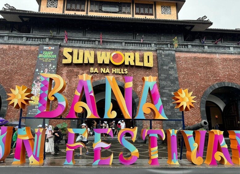 A colorful entrance to Sunworld Ba Na Hills with large letters spelling 'BA NA IN FESTIVAL' and a sign for 'FAIRY BLOSSOM MUST SEE SHOW'. 4