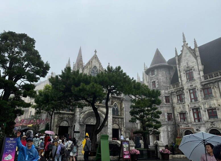 A historic building with Gothic architecture, including pointed arches and spires, surrounded by visitors and trees. 5