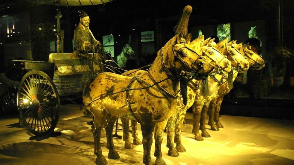 A historical exhibit featuring a chariot with horses and a statue. 3