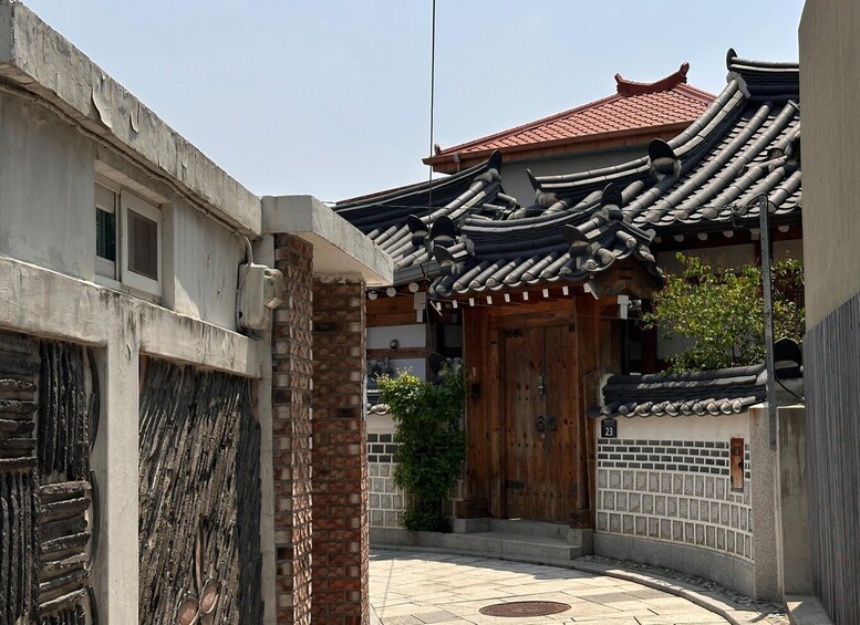 A traditional Korean gate with a tiled roof, a wooden door, and a brick wall. 5