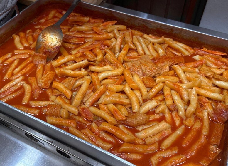 A tray of pasta with a tomato-based sauce and chunks of meat. 3
