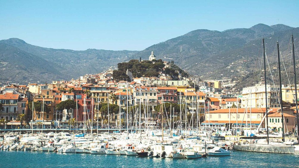 A coastal town with a hilltop church, colorful buildings, and a marina filled with boats. 2