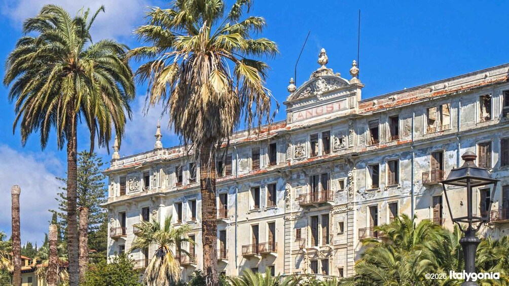A historic building with ornate architecture, palm trees, and a clear blue sky. 4