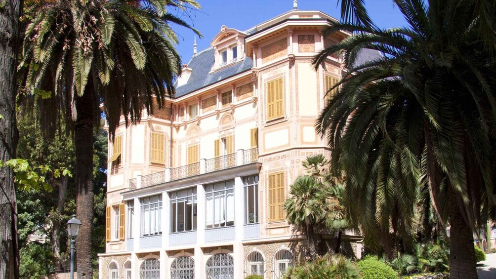 A classical building with ornate balconies and arched windows, surrounded by lush palm trees. 5
