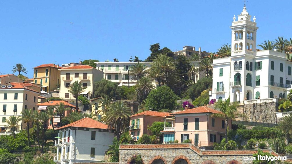 A coastal town with Mediterranean architecture, including a prominent white building with a bell tower. 1