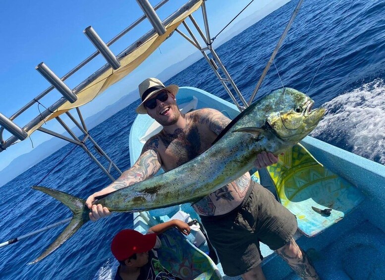 A man holding a large fish on a boat with a clear blue ocean in the background. 3