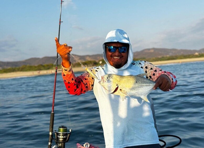 A person holding a fish on a boat, with a fishing rod and a calm sea in the background. 5