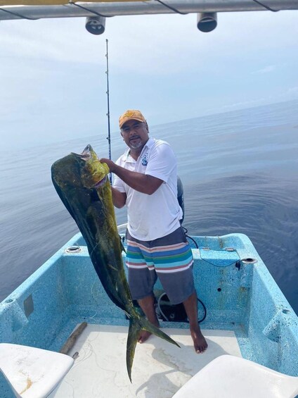 A man holding a large fish on a boat in the ocean. 4
