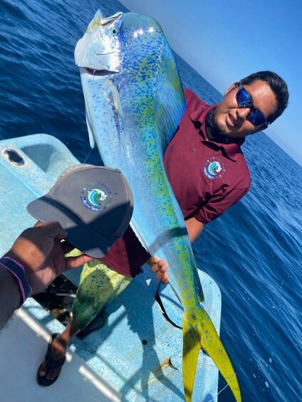 A person holding a large fish on a boat in the ocean. 1