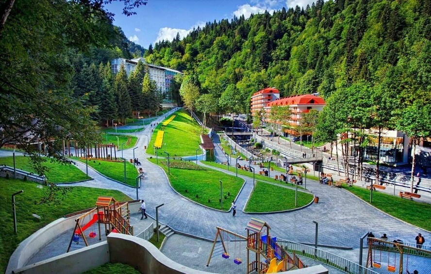 A park with playgrounds, walking paths, and buildings in a mountainous area. 3