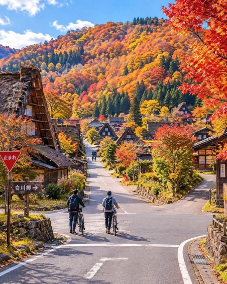 A scenic village with traditional houses, cyclists, and autumn foliage. 2