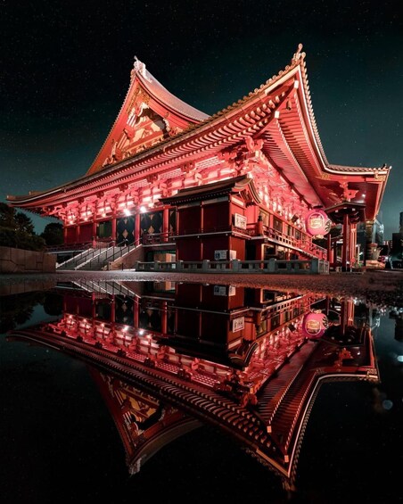 A traditional Japanese building with a reflection in the water at night. 4