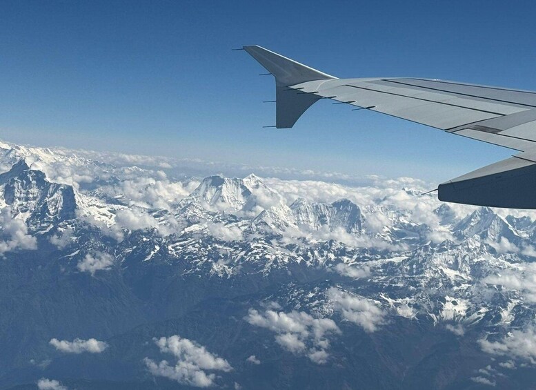 An airplane wing over snow-covered mountains and clouds. 4