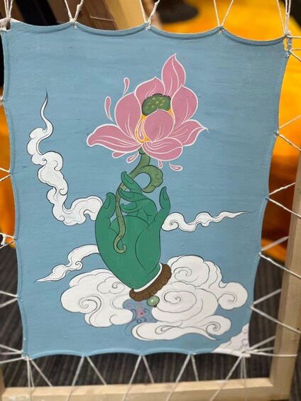 A blue canvas with a pink lotus flower, green leaves, and white clouds. 2
